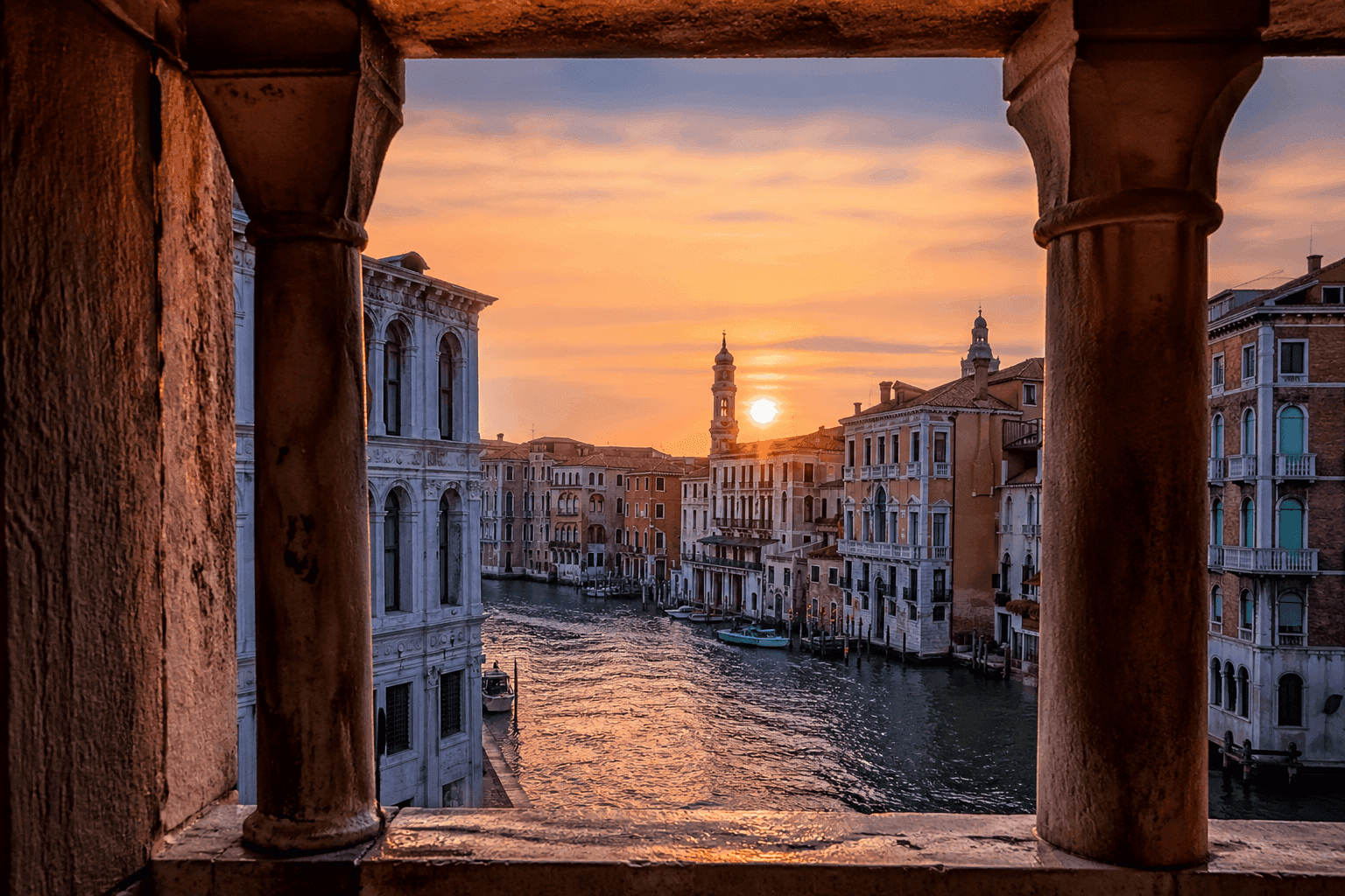Canale veneziano al tramonto incorniciato da antiche colonne